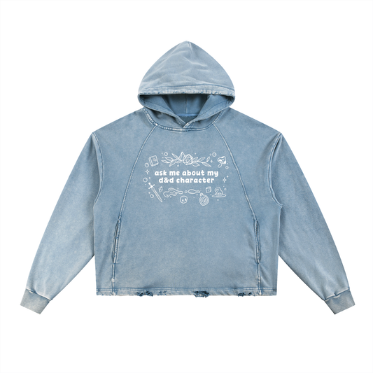 Vintage washed blue oversized fantasy RPG hoodie with white “ask me about my character” graphic surrounded by magical tabletop-inspired doodles including dice, potions, spellbooks, and swords.